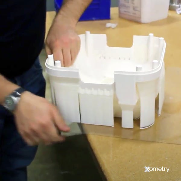 Xometry employee removing support structures from a 3D printed part.