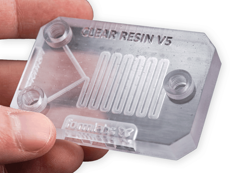 A hand holding a part printed with Formlabs Clear Resin V5.